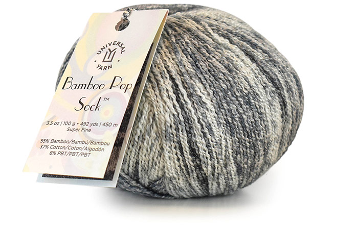 One ball of Bamboo Pop sock in Overcast colorway with the label showing. This colorway consists of white, grays, and black.
