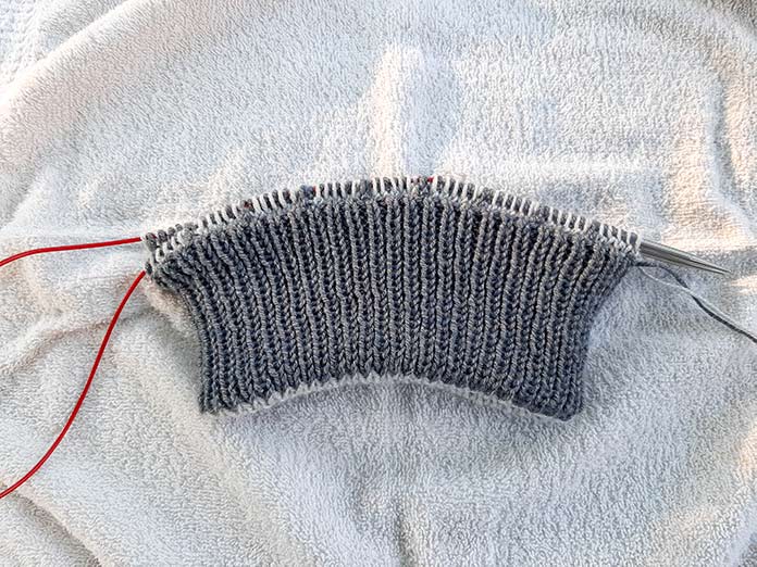 All stitches are on the larger needle after alternating knits and purls from smaller needles.