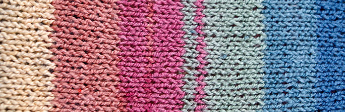 Stockinette swatch of the High Tide colorway of Bamboo Pop Sock with stripes in sand, terracotta, pink, sage green, sky blue and mariner blue.