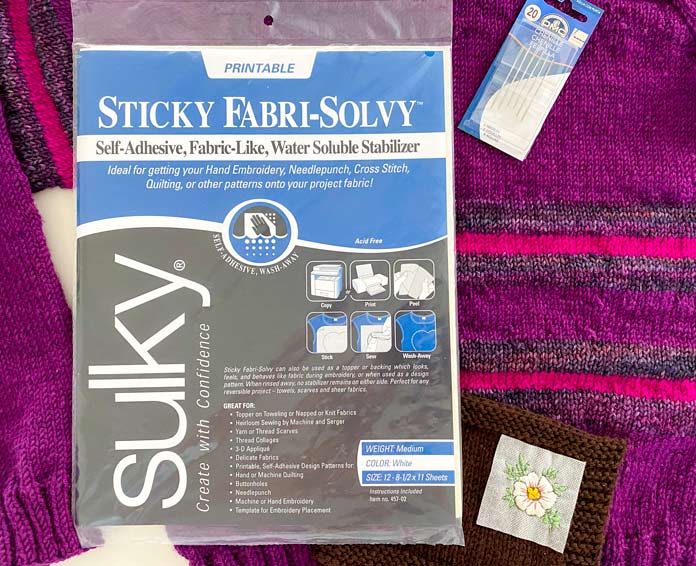 Sulky Sticky Fabri-Solvy package, DMC floss, DMC Chenille needles on a knitted pullover