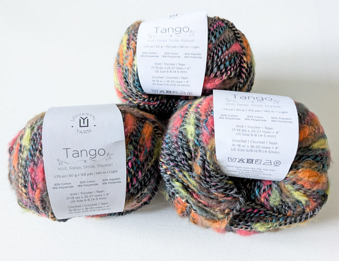 Three balls of the yarn used for the cardigan with labels.