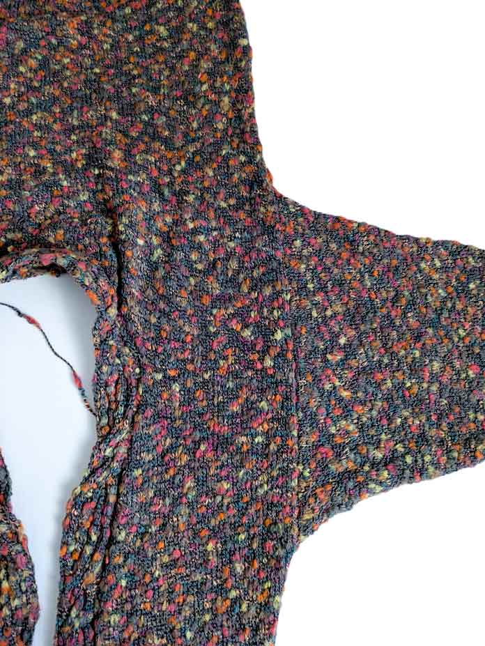A finished cardigan worked in multicolor thick and thin yarn, before closing the side and underarm seams.