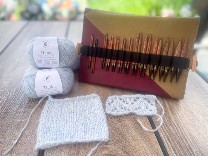 UNIVERSAL YARN Thula in the Delphinium colorway, a knitted swatch in stockinette, a knitted swatch of lace, and the KnitPro Ginger Special Deluxe Interchangeable Needle Kit for the Lace Tipped Cardigan pattern.