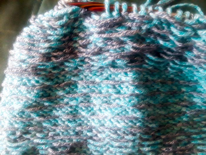 The wrong side of a Holland Cowl, knit in UNIVERSAL YARN Mystical Marl on a set of Knit Picks Rainbow Wood Circular Knitting Needles. The various carried yarns on the wrong side of the stranded colorwork are clearly visible.