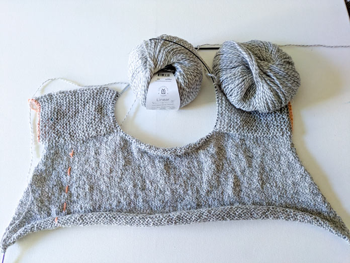 Knitted top down, back of a garment with saddle shoulders.