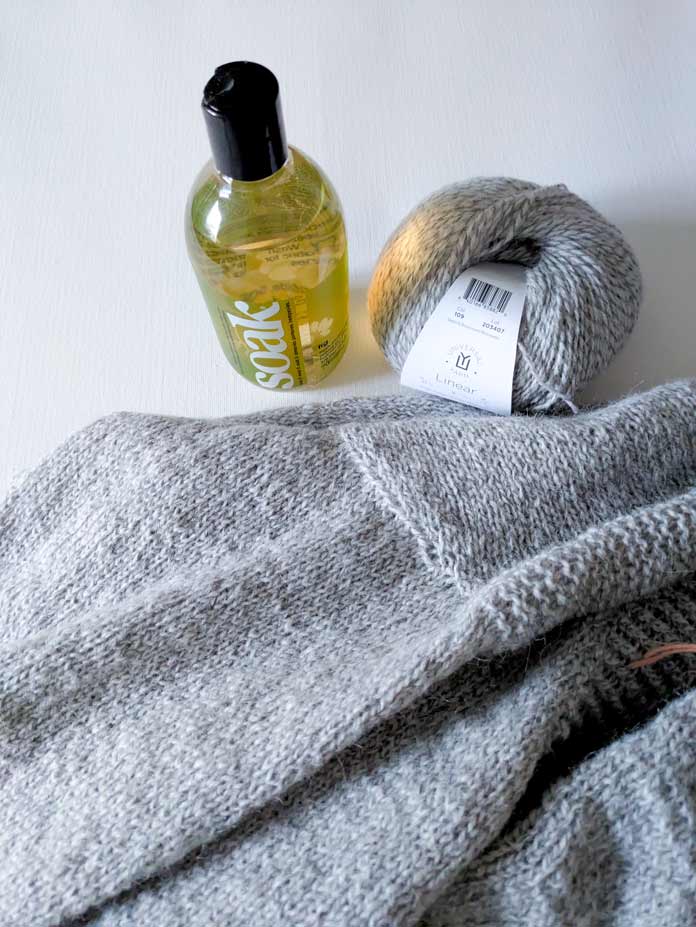 A knitted garment, a ball of yarn and a bottle of wool detergent