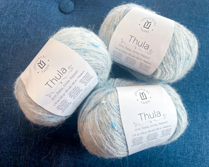 3 balls of yarn on a blue surface.