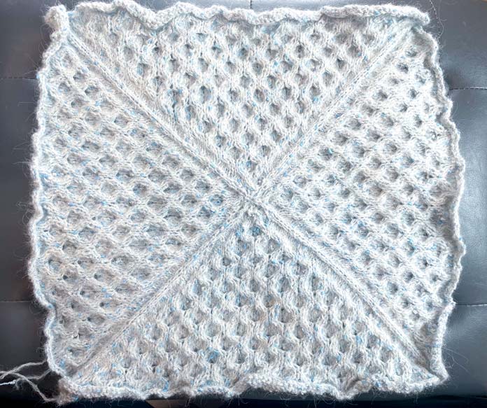 One side of a knitted pillow cover in honeycomb stitch. 