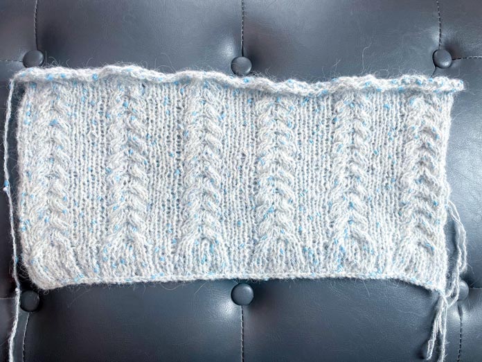 A knitted section of yarn on a gray surface.