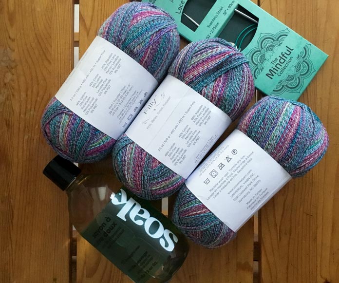 3 skeins of Universal Yarn Filly in variegated blues, pinks, lilacs, and aqua with 1 bottle of Soak wash, and the KNITTER’S PRIDE Mindful Collection knitting needles