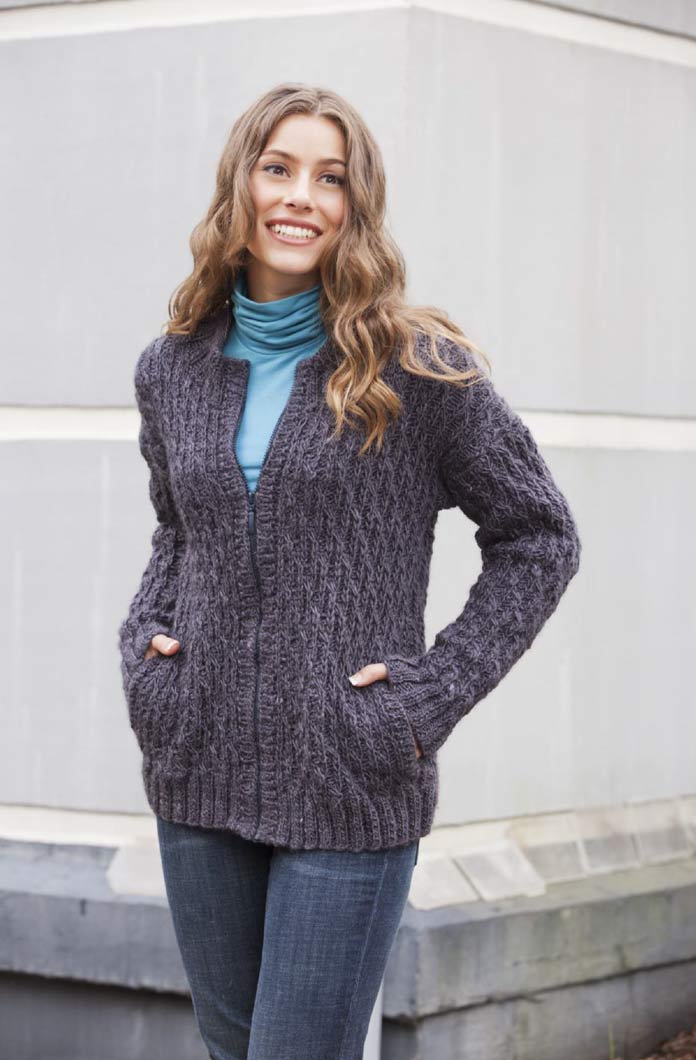 A young woman wearing the knitted Roof Tiles Sweater by Universal Yarn