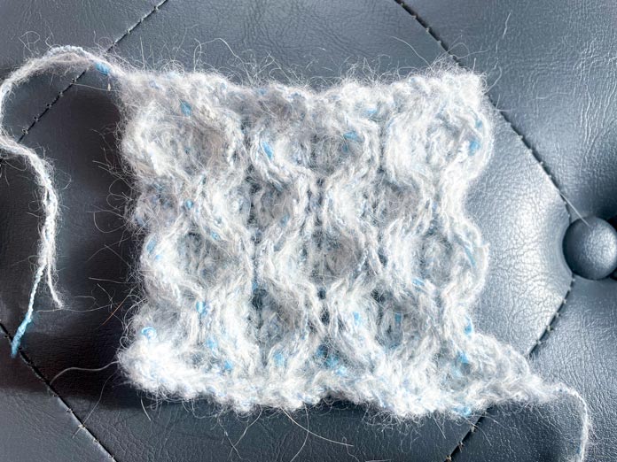 A knitted swatch of yarn in honeycomb stitch. 