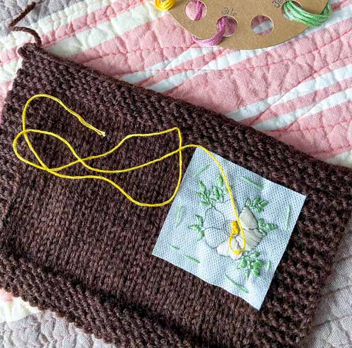 DMC embroidery floss and an unfinished embroidery design on a knitted swatch.