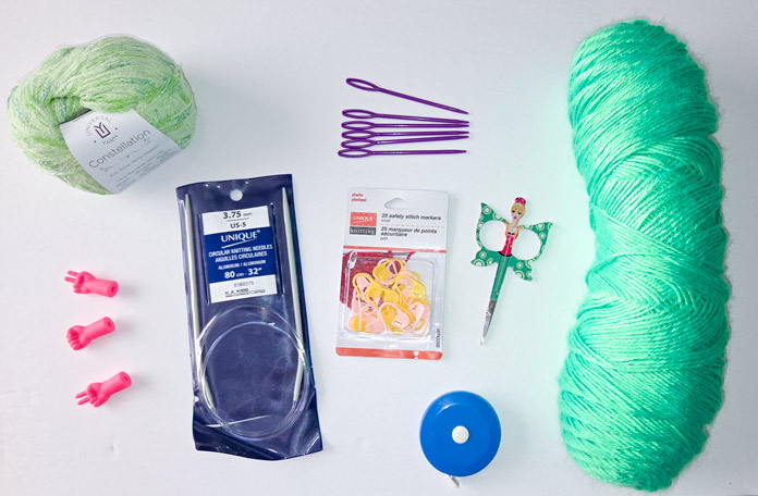 Hydra green yarn, lime green yarn, Unique circular knitting needles, measuring tape, fairy-shaped scissors, pink point protectors, purple bodkin needles.