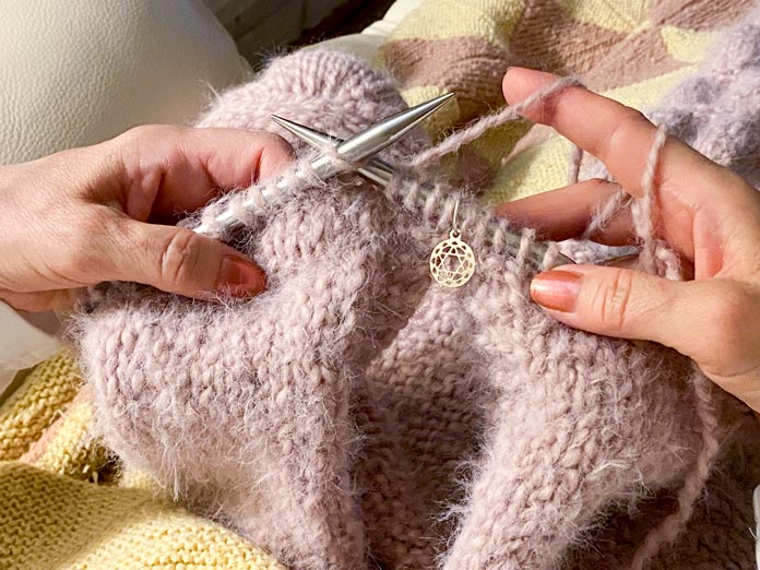 Two hands are knitting the Bubble Sleeve Shrug.