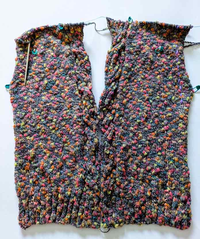 Both fronts of the Lawson Cardigan pattern are worked in multicolor thick and thin cotton blend yarn, showing a cable motif and a V neck.