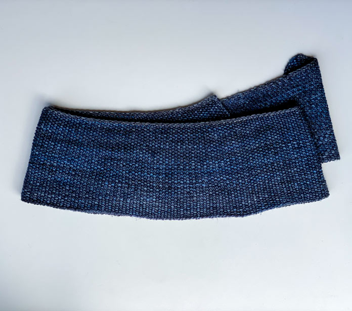 The back of a blue knitted linen stitch scarf