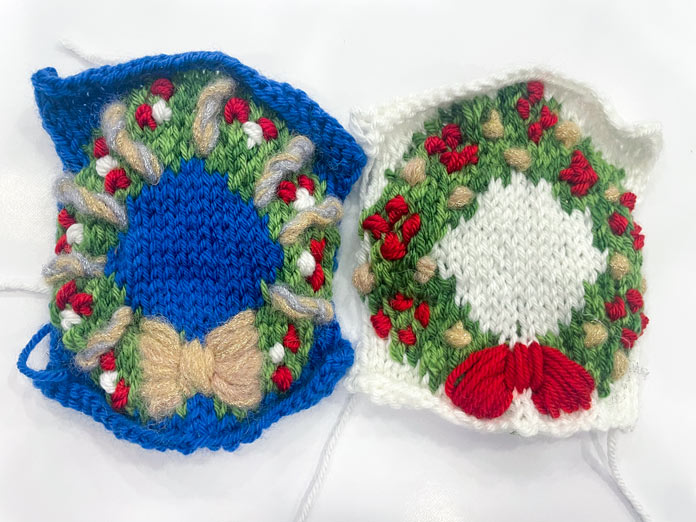 Two knitted Christmas wreath ornaments made with UNIVERSAL YARN Uptown DK and Noelle yarns.