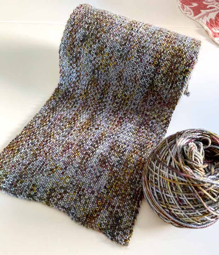 A ball of yarn beside a knitted scarf