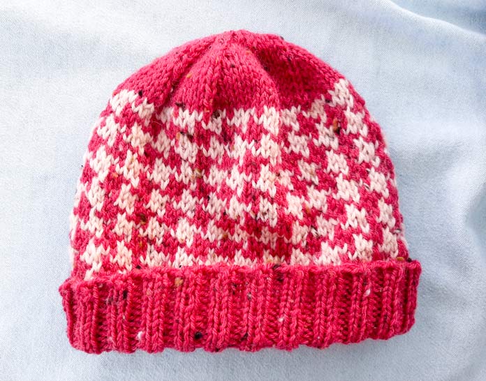 A red and beige knitted hat in a houndstooth pattern; Universal Yarn Deluxe Worsted Tweed Superwash