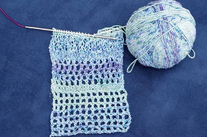 A design swatch featuring 3 different textures, beside a ball of Bamboo Pop Sock yarn.
