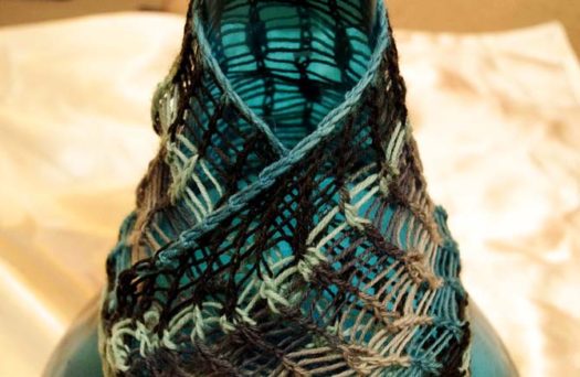 swatch of dropped stitch lace draped over a bottle. Using Prose sock yarn in 'Menswear' colorway