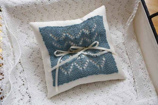 Ring bearer pillow for weddings made with a lace motif on a knitted swatch with 2 ribbons on it using Universal's Flax Lace yarn in mineral