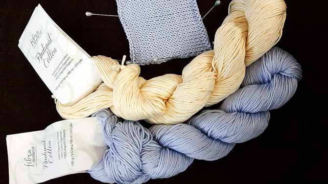 A light periwinkle blue hank and a creamy light custard hank of Radiant cotton beside a stockinette swatch