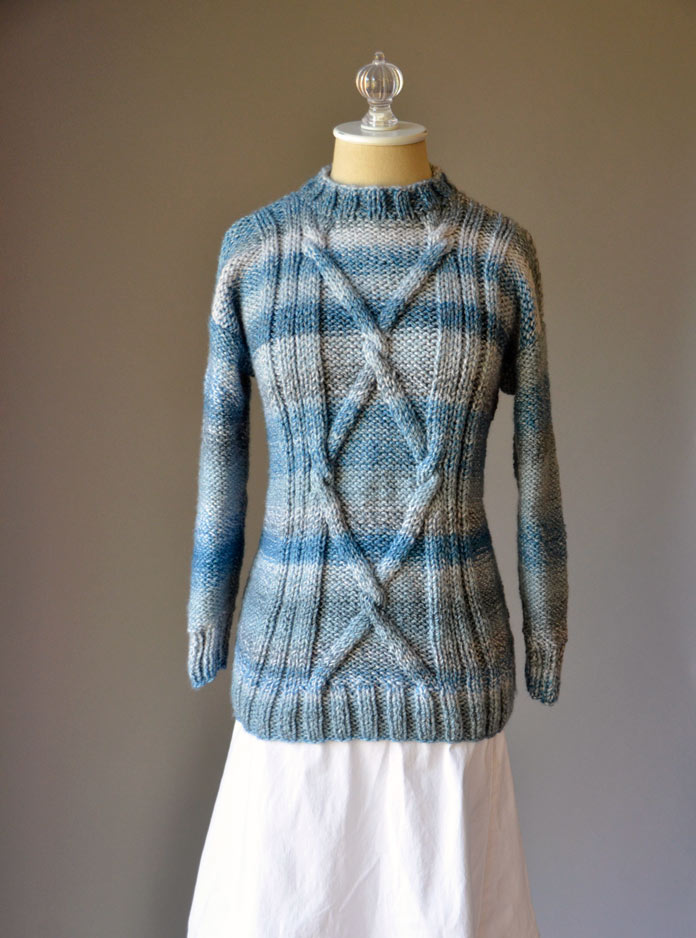 The short tunic length, with the criss-cross cables and ribbing alongside gives the Blue Heartstrings Pullover a svelte silhouette.